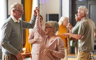 Group of smiling elderly people dancing while enjoying activities.