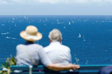 People Sitting on Benches Near Ocean Watching Yacht Race.