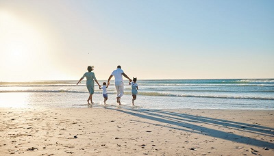 Rearview shot of a happy family walking towards the sea